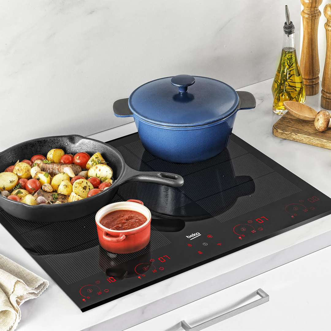 Imagen de la placa de inducción HIIS-63206M de Beko en uso, mostrando las zonas de cocción activas y su funcionalidad durante la preparación de alimentos