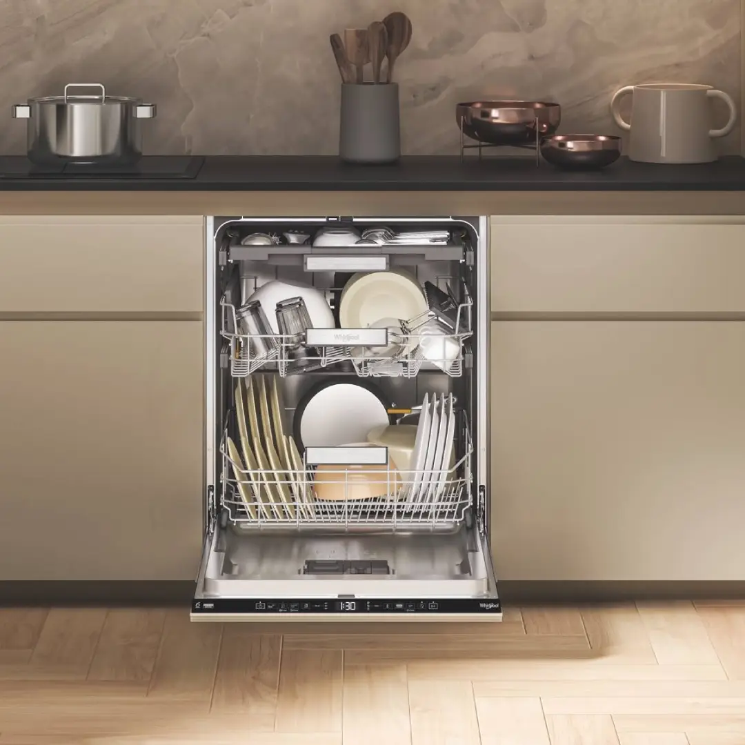 Vista del lavavajillas Whirlpool W7F-HS51 abierto y lleno de platos, integrado en una cocina moderna – disponible en Electrocash.
