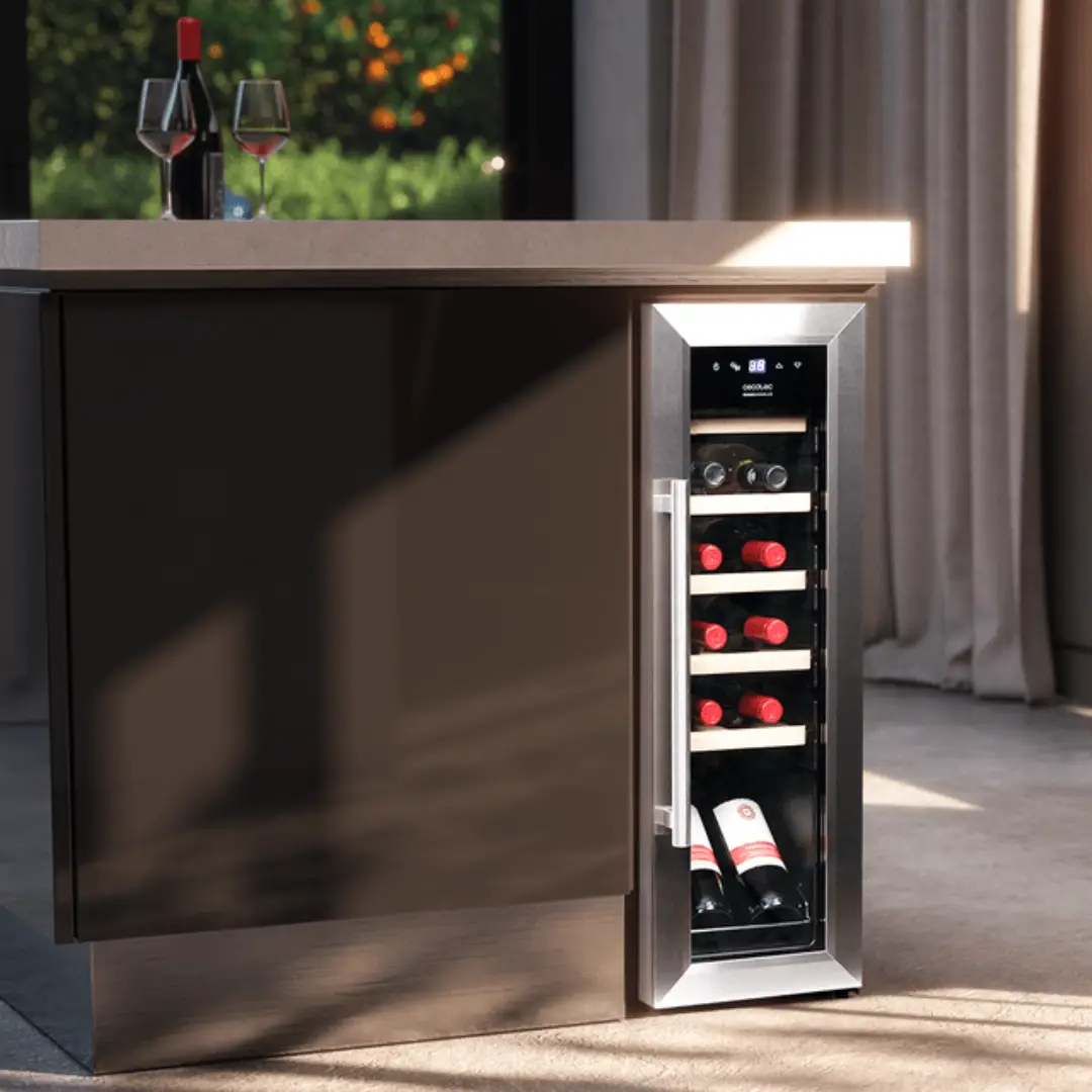 Vinoteca Cecotec GrandSommelier 1250 Inox instalada en una cocina moderna, destacando su acabado metálico elegante, panel táctil superior, iluminación LED interior y baldas de madera, ideal para mantener el vino en condiciones perfectas – imagen ambientada en Electrocash.