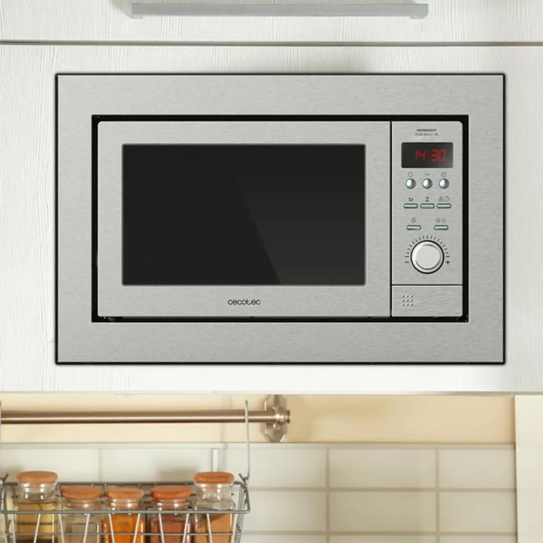 Imagen del microondas de encastre Cecotec GrandHeat 2500 Built-In Steel en acabado inox instalado en una cocina moderna, mostrando su integración en el mobiliario.