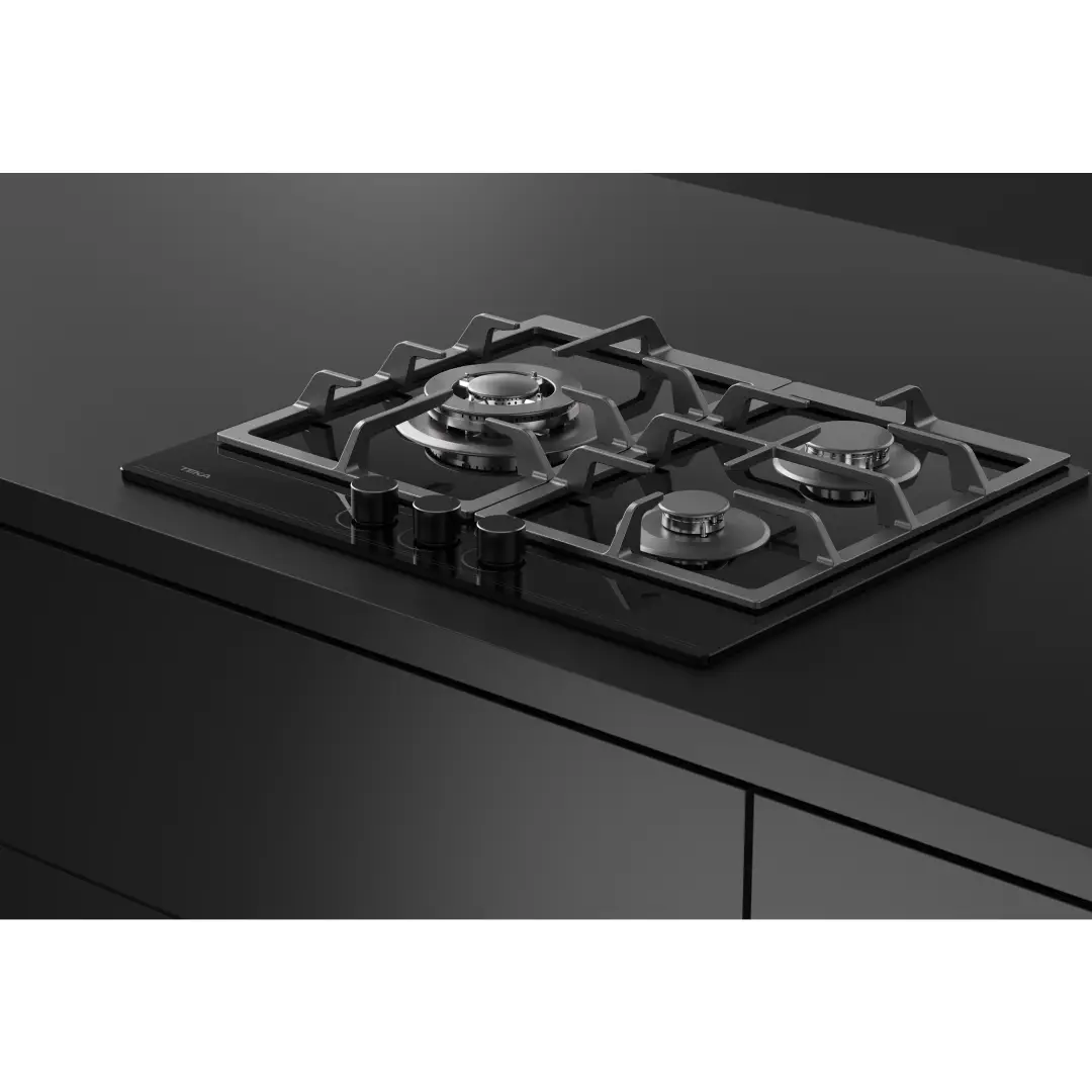 Placa de gas Teka GBC-63110 de 3 fuegos en funcionamiento con utensilios de cocina sobre superficie de cristal negro